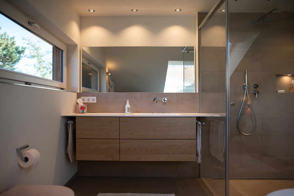 Großes Modernes Badezimmer En Suite mit hellen Holzschränken, Wandtoilette, beigen Fliesen, Steinfliesen, beigem Boden und weißer Waschtischplatte in Sonstige