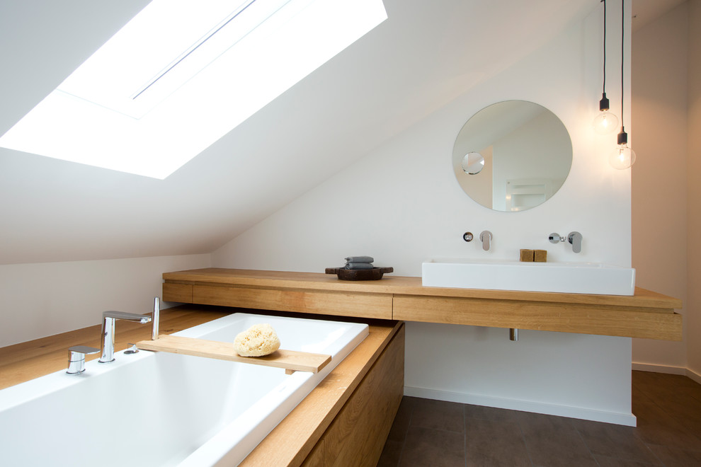 Idée de décoration pour une salle de bain design en bois brun de taille moyenne avec un placard à porte plane, un plan de toilette en bois, une baignoire posée, un carrelage marron, un mur blanc, une vasque et un plan de toilette marron.