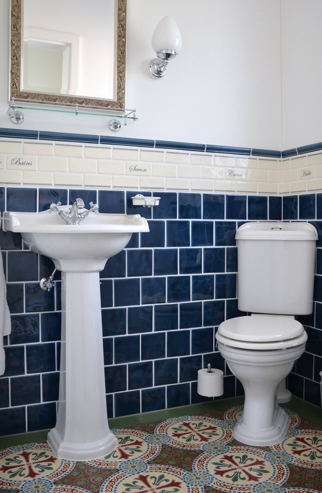 Foto di una stanza da bagno country con WC monopezzo, piastrelle blu, piastrelle in ceramica, pareti bianche, pavimento in cementine, lavabo a consolle e pavimento verde