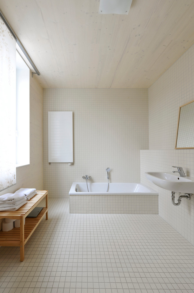 Foto på ett stort funkis badrum, med ett väggmonterat handfat, ett platsbyggt badkar och beige kakel