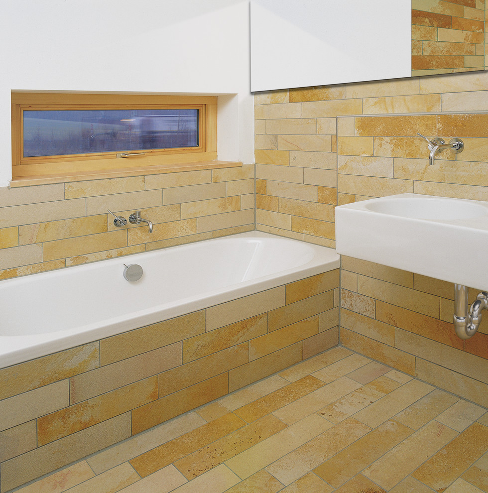 Mittelgroßes Modernes Badezimmer mit Wandwaschbecken, Einbaubadewanne, beigen Fliesen, weißer Wandfarbe und Steinfliesen in Nürnberg