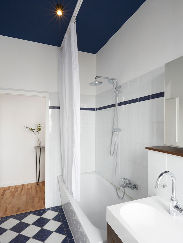 ベルリンにある低価格の中くらいなコンテンポラリースタイルのおしゃれな浴室 (濃色木目調キャビネット、ドロップイン型浴槽、モノトーンのタイル、セラミックタイル、青い壁、セラミックタイルの床、一体型シンク、シャワーカーテン、白い洗面カウンター) の写真