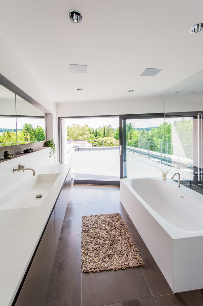 Inspiration för stora moderna badrum, med ett integrerad handfat, bänkskiva i akrylsten, ett fristående badkar, en öppen dusch, en vägghängd toalettstol, brun kakel, stenkakel och vita väggar