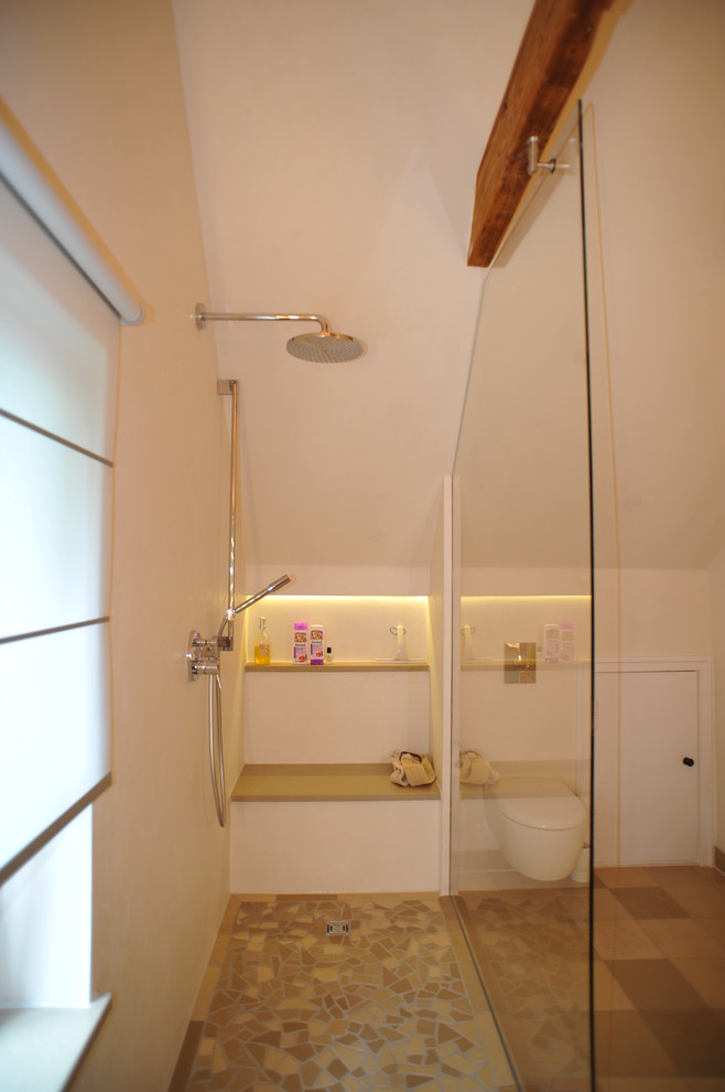 Réalisation d'une petite salle d'eau méditerranéenne avec une douche ouverte, WC suspendus, un carrelage beige et un mur blanc.