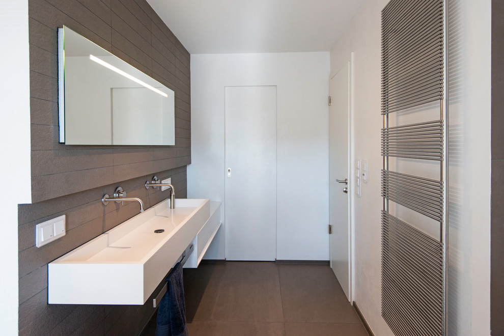 Idéer för ett modernt badrum, med ett avlångt handfat, brun kakel, keramikplattor, vita väggar, klinkergolv i keramik, släta luckor och vita skåp