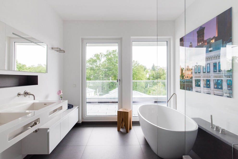 Mittelgroßes Modernes Duschbad mit flächenbündigen Schrankfronten, weißen Schränken, freistehender Badewanne, weißer Wandfarbe, Zementfliesen für Boden, integriertem Waschbecken, Falttür-Duschabtrennung und schwarzem Boden in Frankfurt am Main