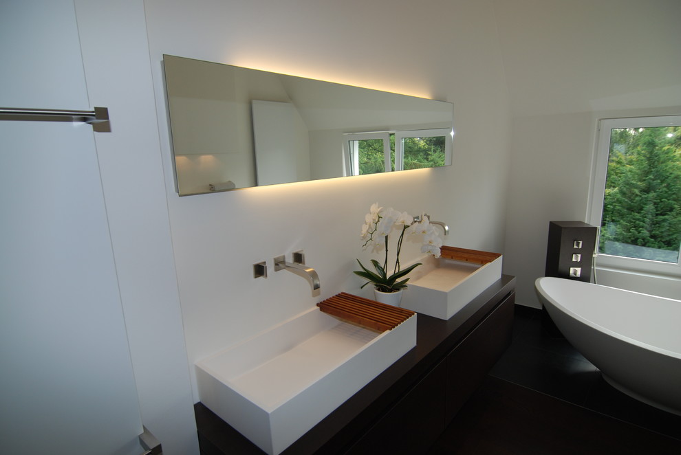 Exempel på ett stort modernt badrum, med ett fristående handfat, träbänkskiva, ett fristående badkar, en kantlös dusch, en vägghängd toalettstol, grå kakel, stenkakel och vita väggar