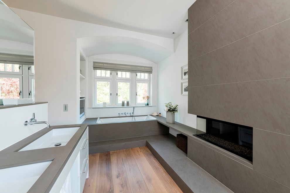 Inspiration för mellanstora moderna en-suite badrum, med släta luckor, vita skåp, ett platsbyggt badkar, vita väggar, mellanmörkt trägolv, ett avlångt handfat och bänkskiva i kvartsit