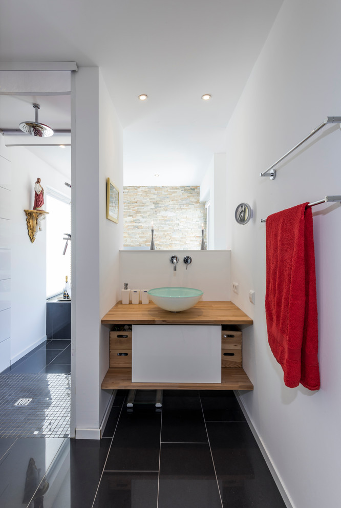 Exemple d'une très grande salle de bain tendance avec une douche à l'italienne, un carrelage noir et blanc, des portes de placard blanches, un mur blanc, une vasque et un plan de toilette en bois.