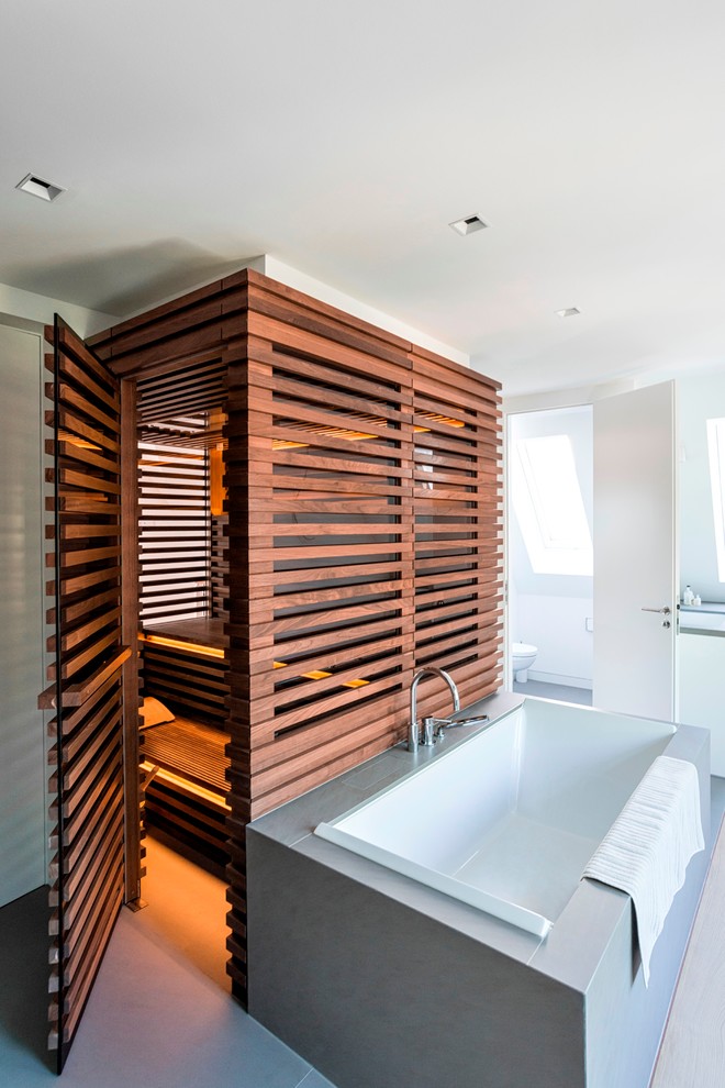 Modernes Badezimmer mit flächenbündigen Schrankfronten, weißen Schränken, freistehender Badewanne, weißer Wandfarbe, hellem Holzboden, Trogwaschbecken und Quarzit-Waschtisch in Hamburg