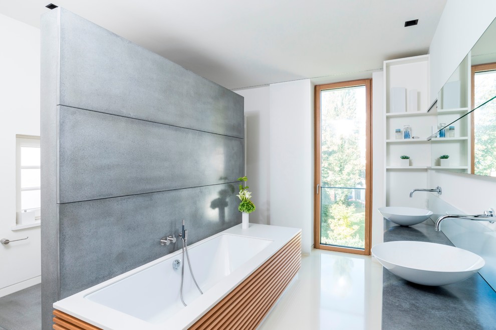 ハンブルクにあるコンテンポラリースタイルのおしゃれなマスターバスルーム (フラットパネル扉のキャビネット、白いキャビネット、アンダーマウント型浴槽、白い壁、ベッセル式洗面器、コンクリートの洗面台、クッションフロア) の写真