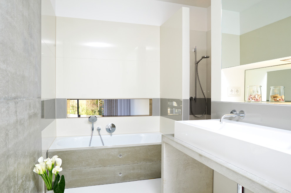 Idéer för ett mellanstort modernt badrum, med bänkskiva i betong, vit kakel, keramikplattor, vita väggar, ett avlångt handfat och ett badkar i en alkov