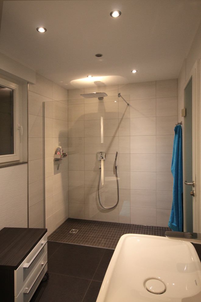 Imagen de cuarto de baño contemporáneo pequeño con lavabo sobreencimera, ducha a ras de suelo, sanitario de pared, baldosas y/o azulejos grises, paredes blancas, suelo de baldosas de porcelana y aseo y ducha