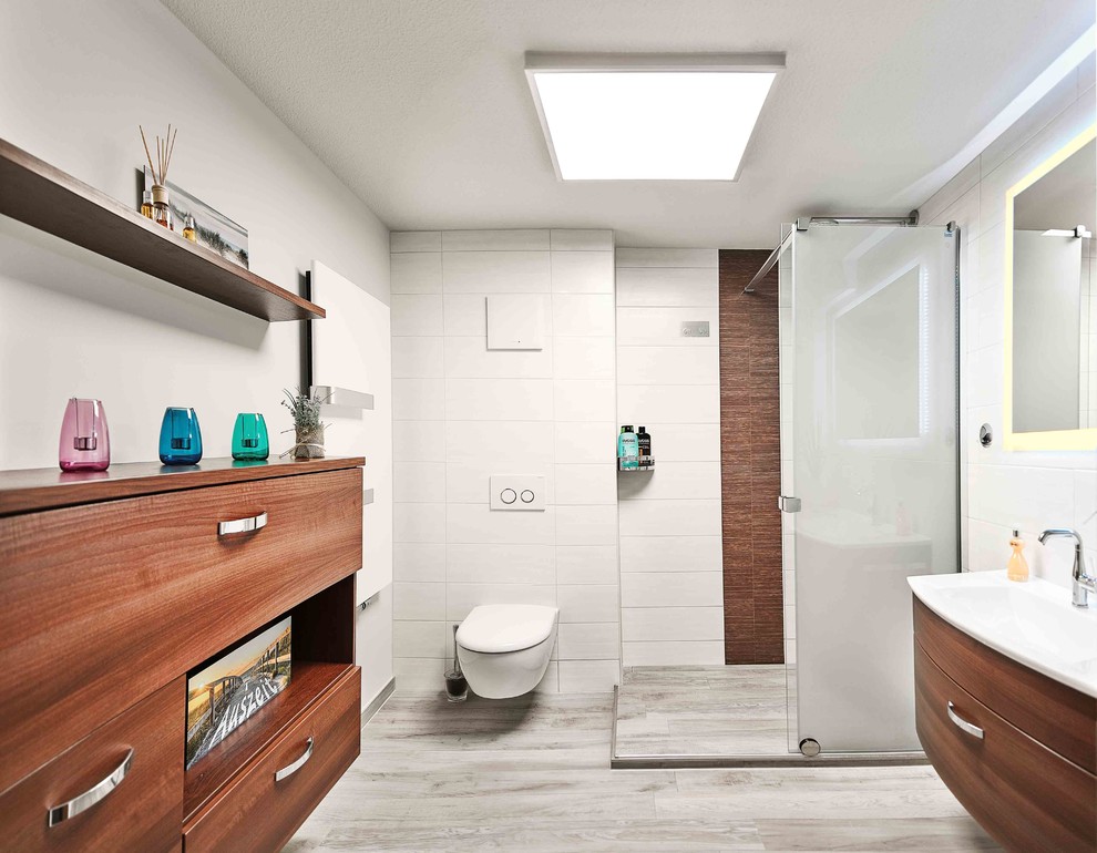 Пример оригинального дизайна: маленькая ванная комната в современном стиле с плоскими фасадами, темными деревянными фасадами, угловым душем, инсталляцией, белой плиткой, белыми стенами, монолитной раковиной и душем с раздвижными дверями для на участке и в саду