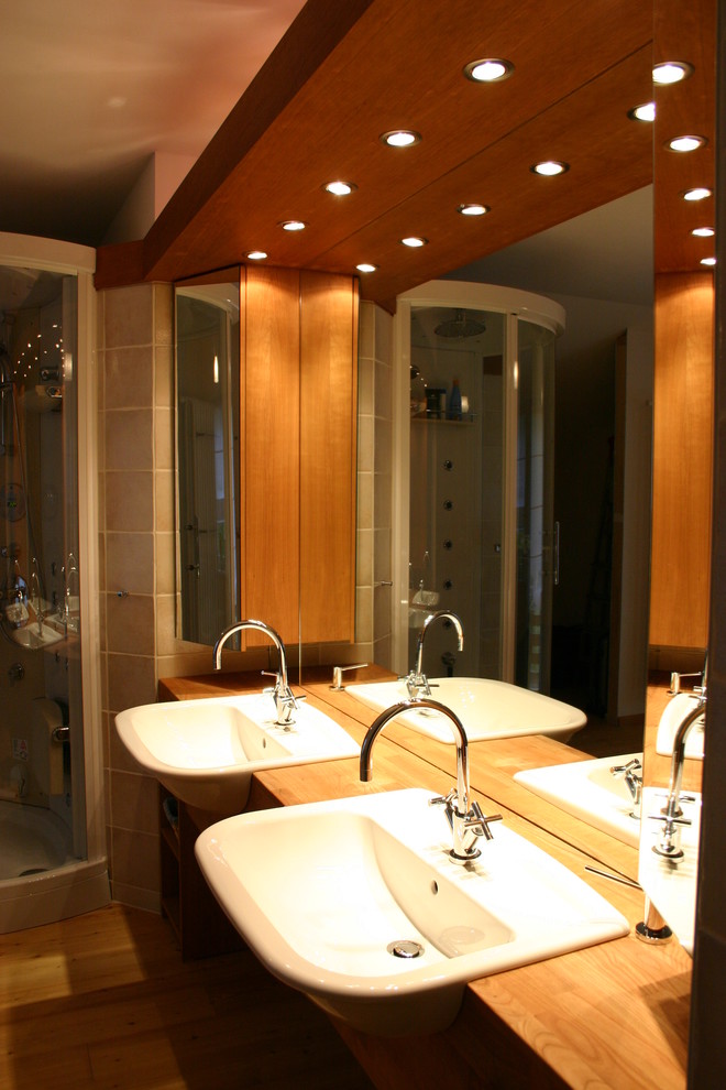 Großes Modernes Badezimmer mit Glasfronten, dunklen Holzschränken, freistehender Badewanne, Urinal, Keramikfliesen, hellem Holzboden, Aufsatzwaschbecken und Waschtisch aus Holz in München