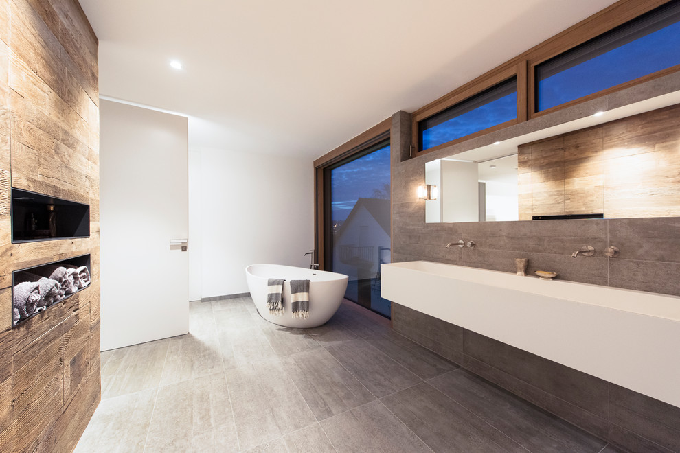 Foto de cuarto de baño actual grande con bañera exenta, paredes blancas, lavabo suspendido y suelo gris