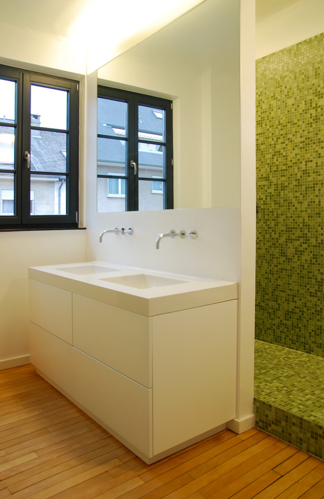 This is an example of a medium sized contemporary bathroom in Other with white cabinets, a walk-in shower, green tiles, mosaic tiles, white walls, medium hardwood flooring, a trough sink and limestone worktops.