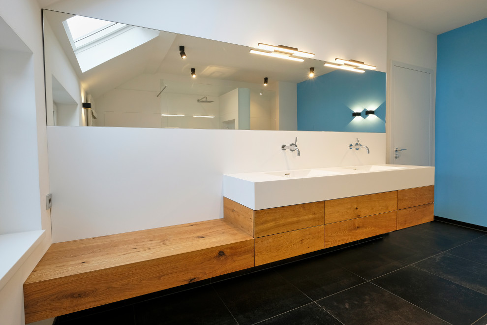 Idée de décoration pour une grande salle de bain design en bois clair avec une baignoire posée, une douche à l'italienne, WC séparés, un carrelage blanc, des carreaux de céramique, un mur bleu, un sol en carrelage de céramique, un lavabo posé, un sol noir, aucune cabine et un plan de toilette blanc.
