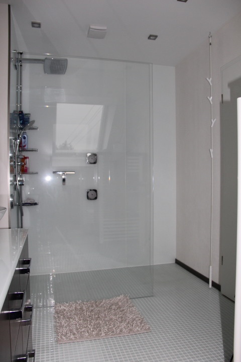 Foto på ett mellanstort funkis badrum med dusch, med släta luckor, bruna skåp, en kantlös dusch, en toalettstol med separat cisternkåpa, ett fristående handfat, bänkskiva i glas och med dusch som är öppen