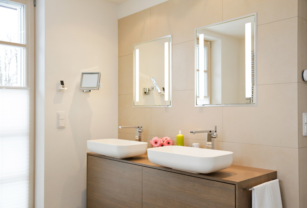 Large contemporary shower room bathroom in Munich with flat-panel cabinets, beige tiles, white walls, a vessel sink, wooden worktops, brown cabinets, a freestanding bath, a built-in shower, a wall mounted toilet, brown floors and a hinged door.