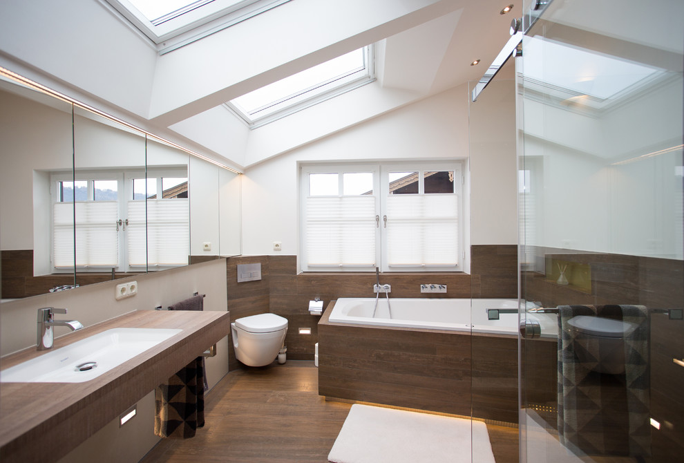 Diseño de cuarto de baño actual de tamaño medio con bañera esquinera, paredes blancas, lavabo encastrado, encimera de madera y suelo de madera oscura