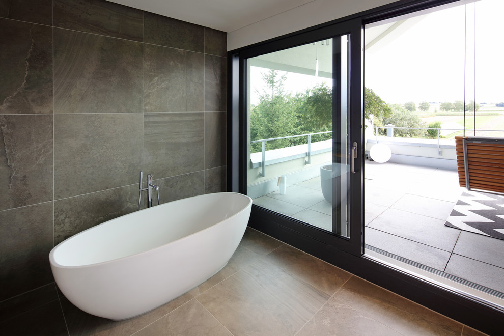 Imagen de cuarto de baño moderno grande con bañera exenta, ducha a ras de suelo, sanitario de dos piezas, paredes grises, lavabo sobreencimera, suelo beige y ducha abierta