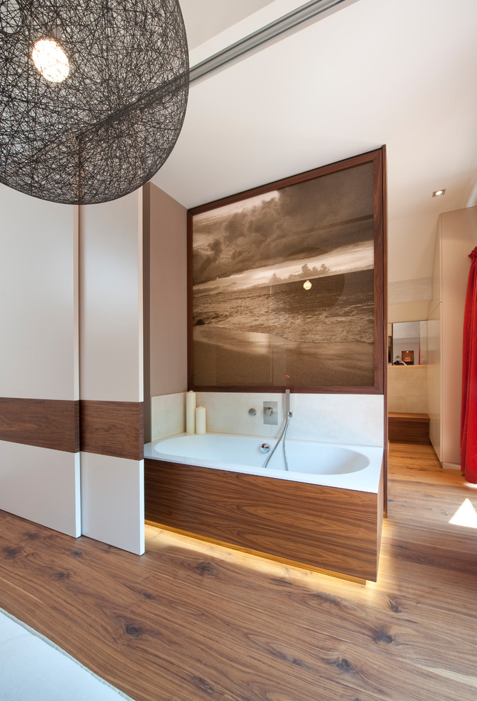 Immagine di una grande stanza da bagno padronale contemporanea con vasca da incasso, piastrelle beige, pareti marroni, pavimento in legno massello medio e pavimento marrone