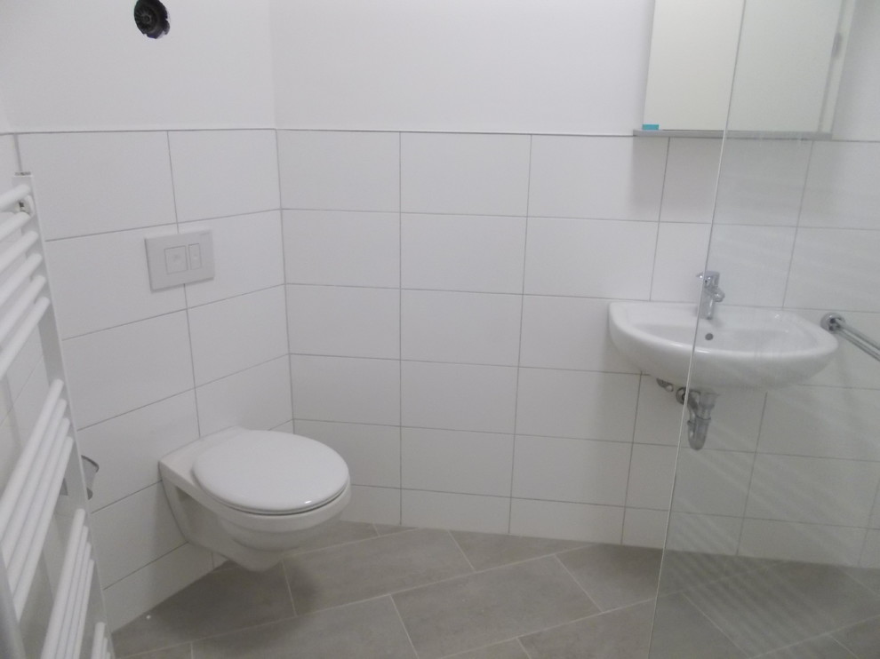На фото: маленькая ванная комната в современном стиле с душем в нише, инсталляцией, белой плиткой, керамической плиткой, белыми стенами, полом из керамической плитки, душевой кабиной и подвесной раковиной для на участке и в саду