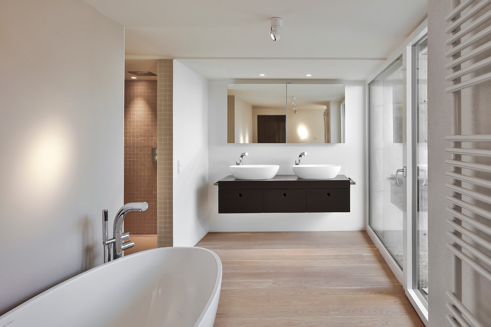 Esempio di una stanza da bagno design con ante lisce, ante nere, vasca freestanding, doccia alcova, piastrelle grigie, piastrelle a mosaico, parquet chiaro, lavabo a bacinella e top in legno