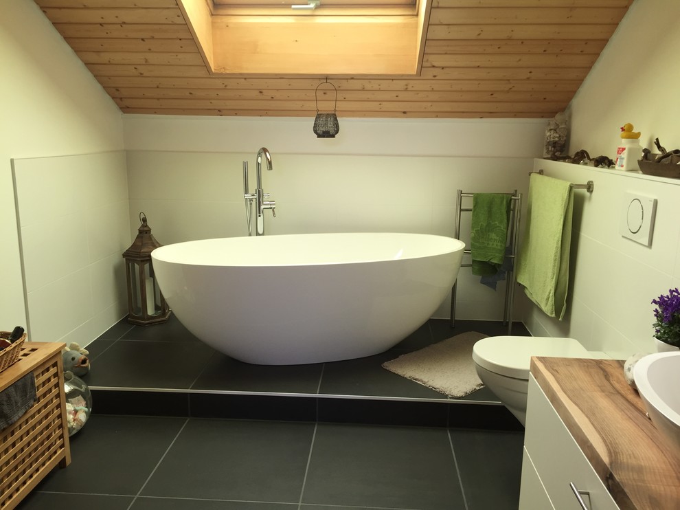 Idéer för ett modernt badrum, med ett fristående badkar, vit kakel, vita väggar, cementgolv, ett fristående handfat, bänkskiva i akrylsten och grått golv