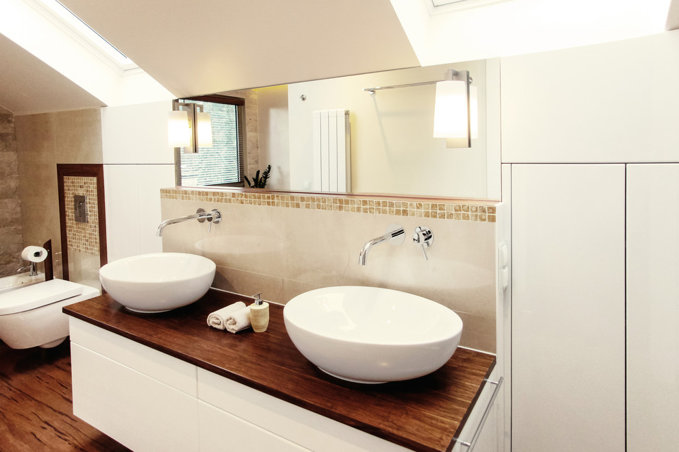 Design ideas for a medium sized contemporary bathroom in Berlin with a wall mounted toilet, ceramic tiles, beige walls, bamboo flooring, a vessel sink, flat-panel cabinets, white cabinets, beige tiles, wooden worktops and brown worktops.