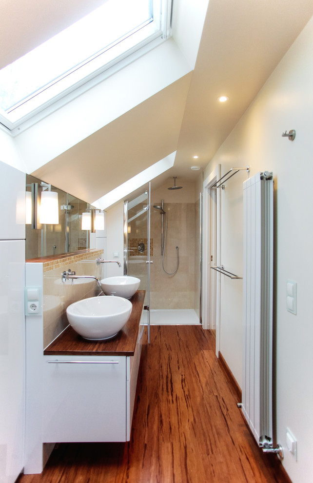 На фото: ванная комната среднего размера в современном стиле с плоскими фасадами, белыми фасадами, бежевой плиткой, керамической плиткой, бежевыми стенами, полом из бамбука, настольной раковиной и столешницей из дерева с