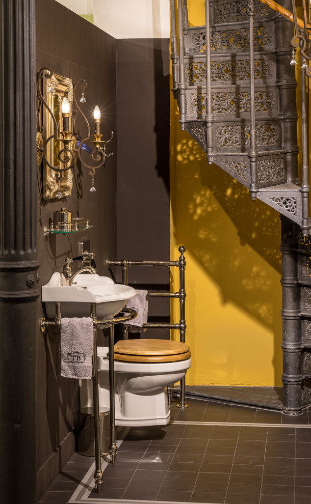 Mittelgroßes Klassisches Badezimmer mit freistehender Badewanne, Wandtoilette mit Spülkasten, gelber Wandfarbe, Keramikboden, Waschtischkonsole und braunem Boden in München