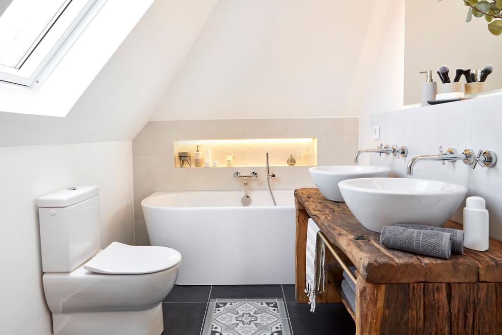 Small farmhouse ensuite bathroom in Other with a one-piece toilet, white tiles, white walls, a vessel sink, wooden worktops, black floors, brown worktops, open cabinets, dark wood cabinets, a freestanding bath, ceramic flooring, a shower/bath combination and an open shower.