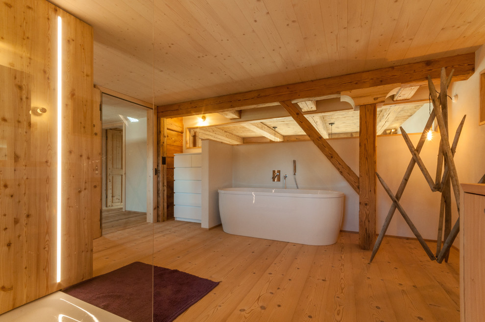 Exemple d'une grande salle d'eau nature en bois brun avec un placard sans porte, une baignoire indépendante, un combiné douche/baignoire, WC suspendus, un mur blanc, parquet foncé, une vasque et un plan de toilette en surface solide.