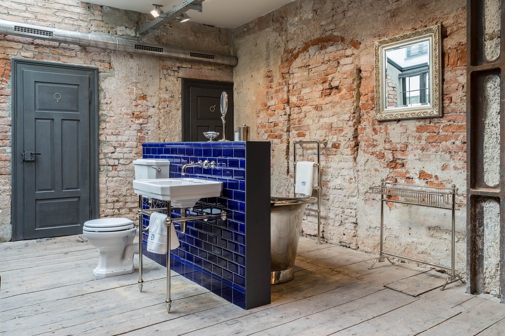 Idéer för att renovera ett mellanstort industriellt badrum med dusch, med ett fristående badkar, blå kakel, keramikplattor, ett konsol handfat, en toalettstol med separat cisternkåpa, ljust trägolv, grått golv, en dusch/badkar-kombination, röda väggar och bänkskiva i akrylsten