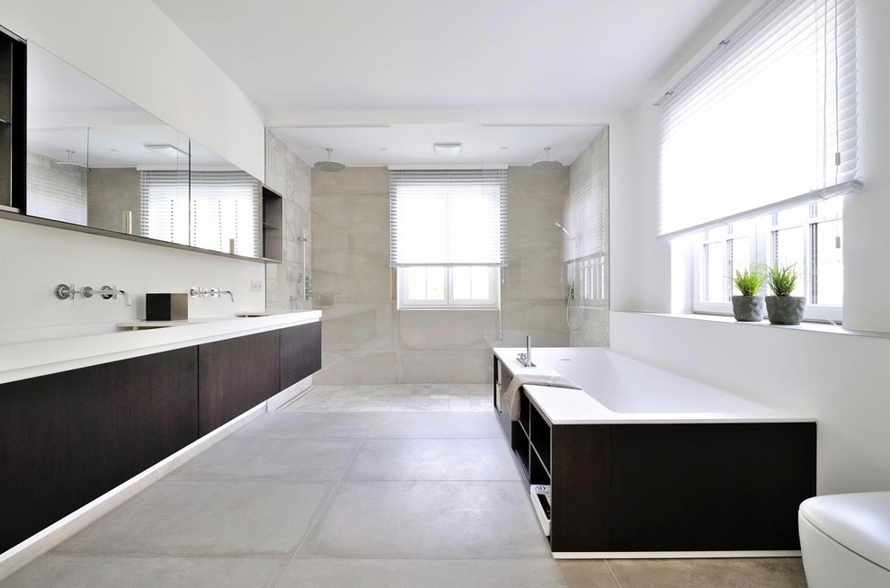 Large trendy 3/4 gray tile and porcelain tile pebble tile floor and beige floor bathroom photo in Munich with dark wood cabinets, a wall-mount toilet, white walls, flat-panel cabinets, a trough sink and wood countertops