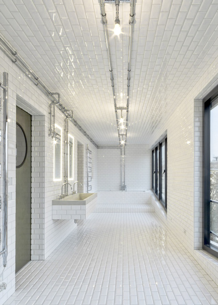 Foto på ett industriellt badrum med dusch, med ett badkar i en alkov, vit kakel, tunnelbanekakel, vita väggar, klinkergolv i keramik och ett avlångt handfat