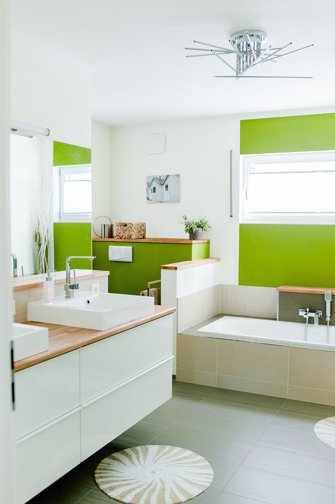Пример оригинального дизайна: ванная комната среднего размера в современном стиле с белыми фасадами, накладной ванной, открытым душем, раздельным унитазом, бежевой плиткой, керамической плиткой, зелеными стенами, полом из керамогранита, настольной раковиной, столешницей из искусственного камня, серым полом и коричневой столешницей
