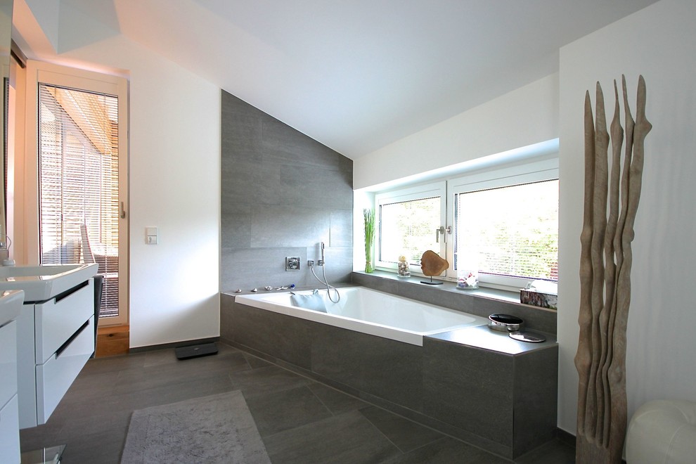 Пример оригинального дизайна: главная ванная комната среднего размера в современном стиле с плоскими фасадами, белыми фасадами, угловой ванной, цементной плиткой, белыми стенами и столешницей из искусственного камня