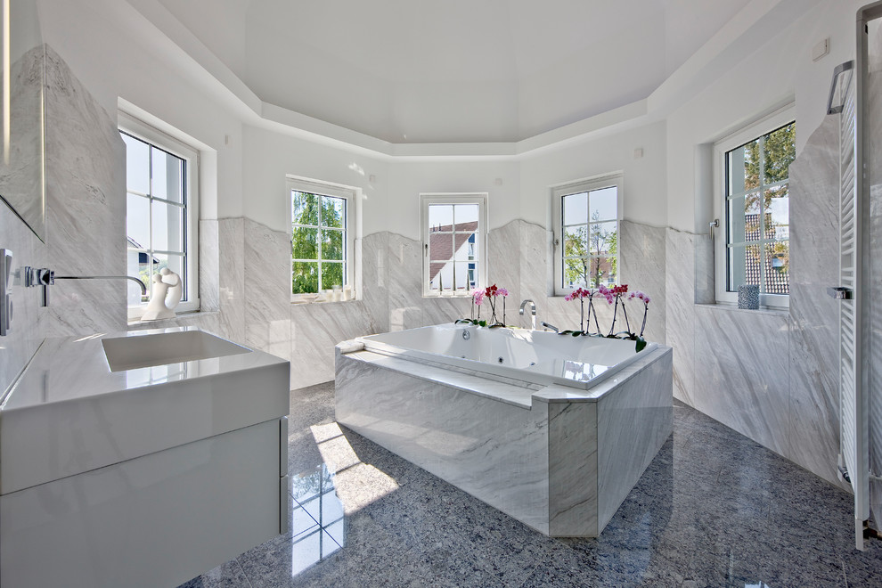 Inspiration för mellanstora moderna en-suite badrum, med ett integrerad handfat, ett platsbyggt badkar, grå kakel, vita väggar, släta luckor och vita skåp