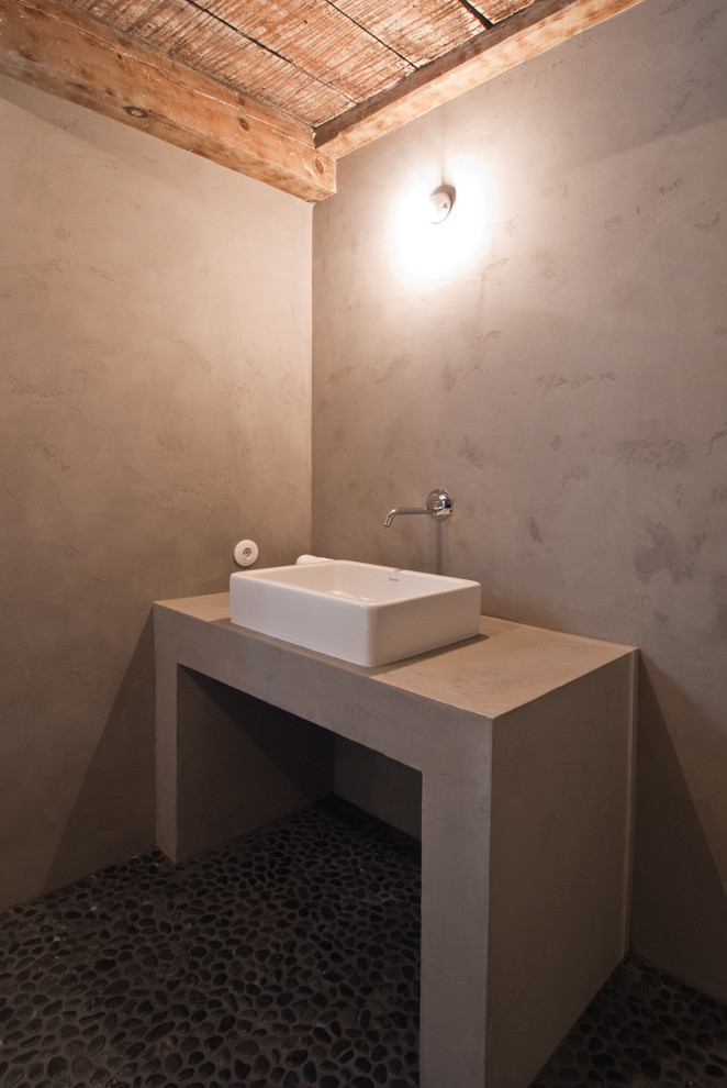Foto de cuarto de baño rústico de tamaño medio con ducha a ras de suelo, sanitario de pared, paredes grises, suelo de baldosas tipo guijarro, aseo y ducha y lavabo sobreencimera