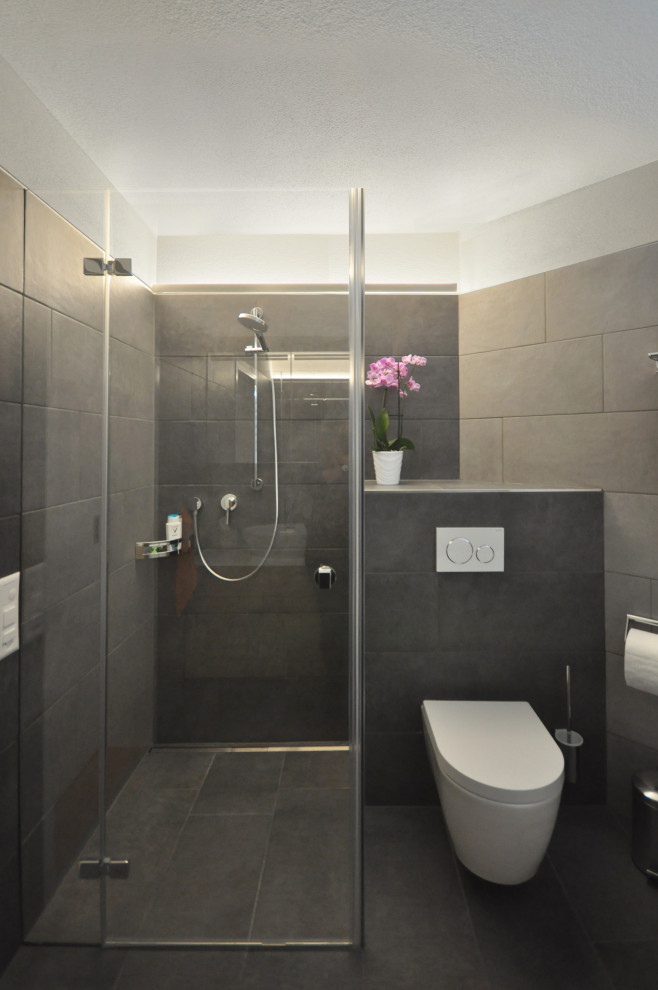 Exempel på ett modernt vit vitt badrum, med skåp i mellenmörkt trä, ett platsbyggt badkar, en kantlös dusch, en toalettstol med separat cisternkåpa, grå kakel, keramikplattor, grå väggar, klinkergolv i keramik, ett fristående handfat, bänkskiva i akrylsten, grått golv och dusch med gångjärnsdörr