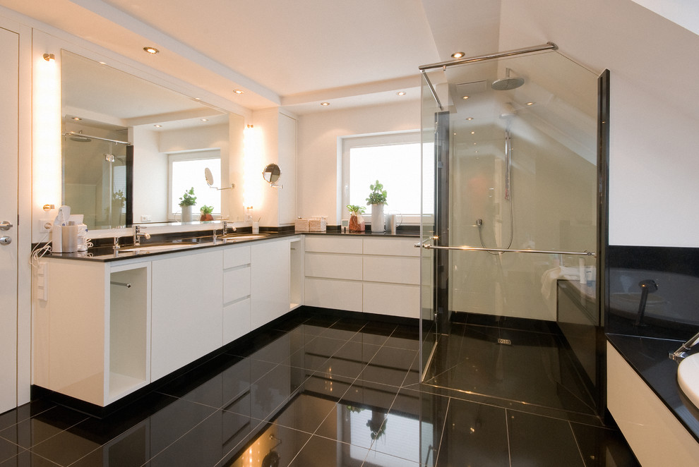 Photo of a medium sized contemporary bathroom in Cologne with flat-panel cabinets, white cabinets, a built-in shower, white walls, black floors and a hinged door.