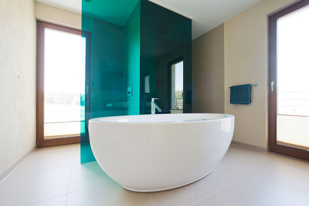 На фото: большая ванная комната в современном стиле с серой плиткой, бежевыми стенами и отдельно стоящей ванной с