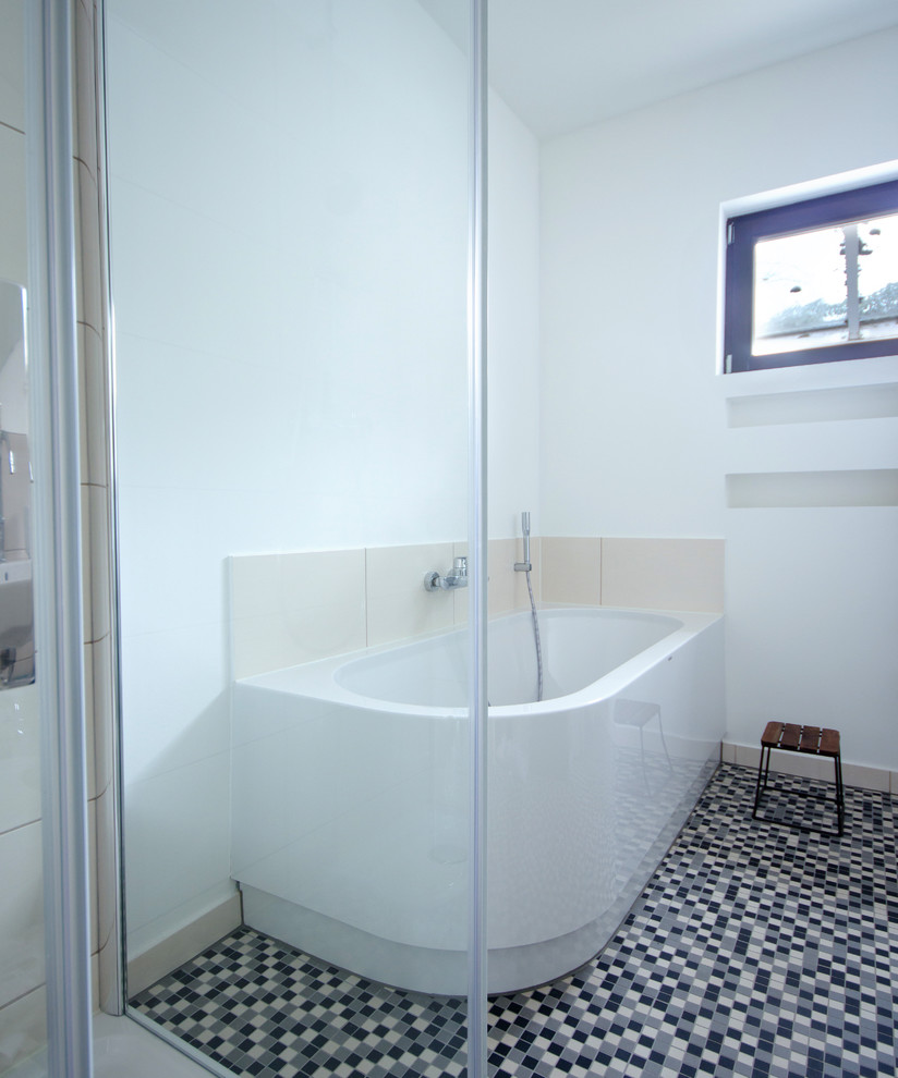 Idéer för mellanstora funkis grått badrum med dusch, med släta luckor, vita skåp, ett hörnbadkar, en kantlös dusch, en vägghängd toalettstol, beige kakel, keramikplattor, vita väggar, mosaikgolv, ett nedsänkt handfat, bänkskiva i betong, svart golv och dusch med gångjärnsdörr