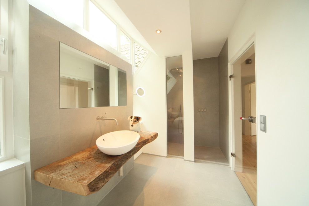 На фото: ванная комната в современном стиле с настольной раковиной и столешницей из дерева с
