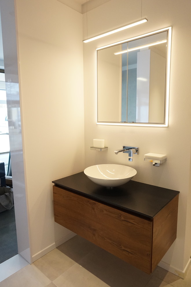 Esempio di una stanza da bagno minimal di medie dimensioni con ante lisce, ante in legno scuro, lavabo a bacinella e top in superficie solida