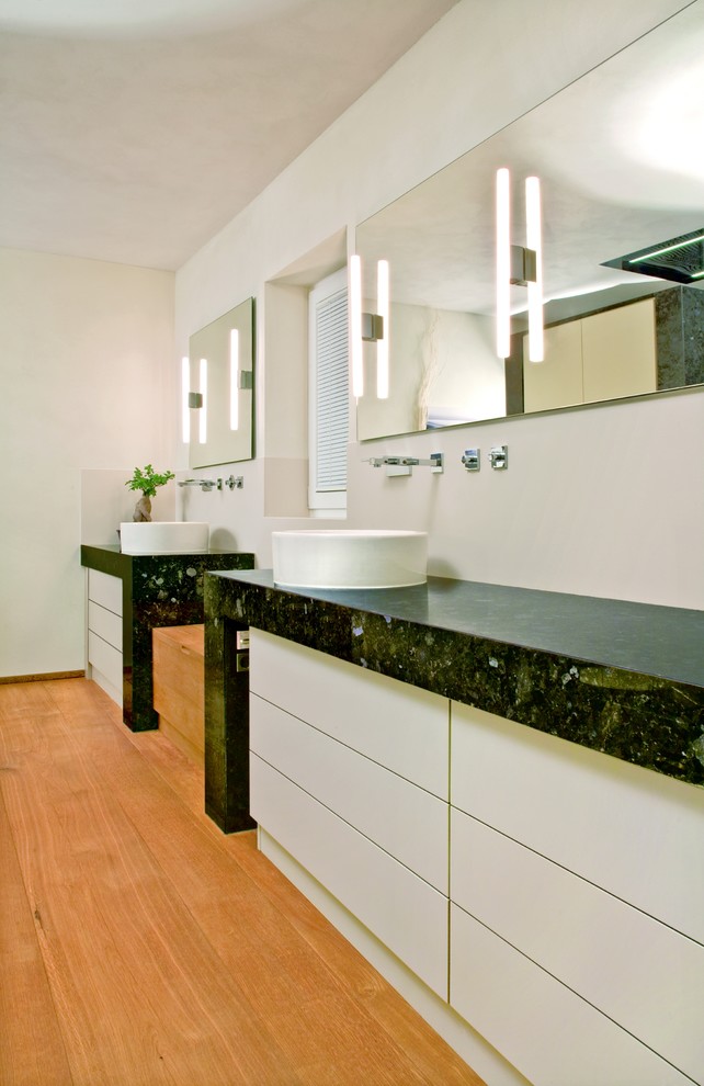 Großes Modernes Badezimmer mit flächenbündigen Schrankfronten, weißen Schränken, hellem Holzboden, Aufsatzwaschbecken und Granit-Waschbecken/Waschtisch in Frankfurt am Main