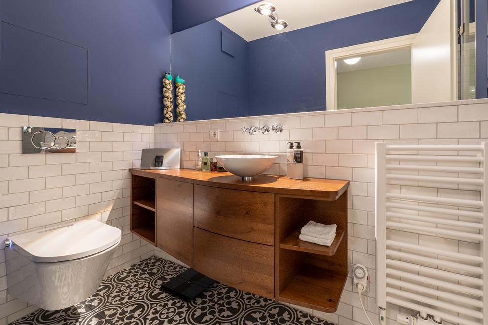 Medium sized mediterranean ensuite bathroom in Munich with flat-panel cabinets, medium wood cabinets, white tiles, ceramic tiles, blue walls, ceramic flooring, a vessel sink, wooden worktops and a hinged door.